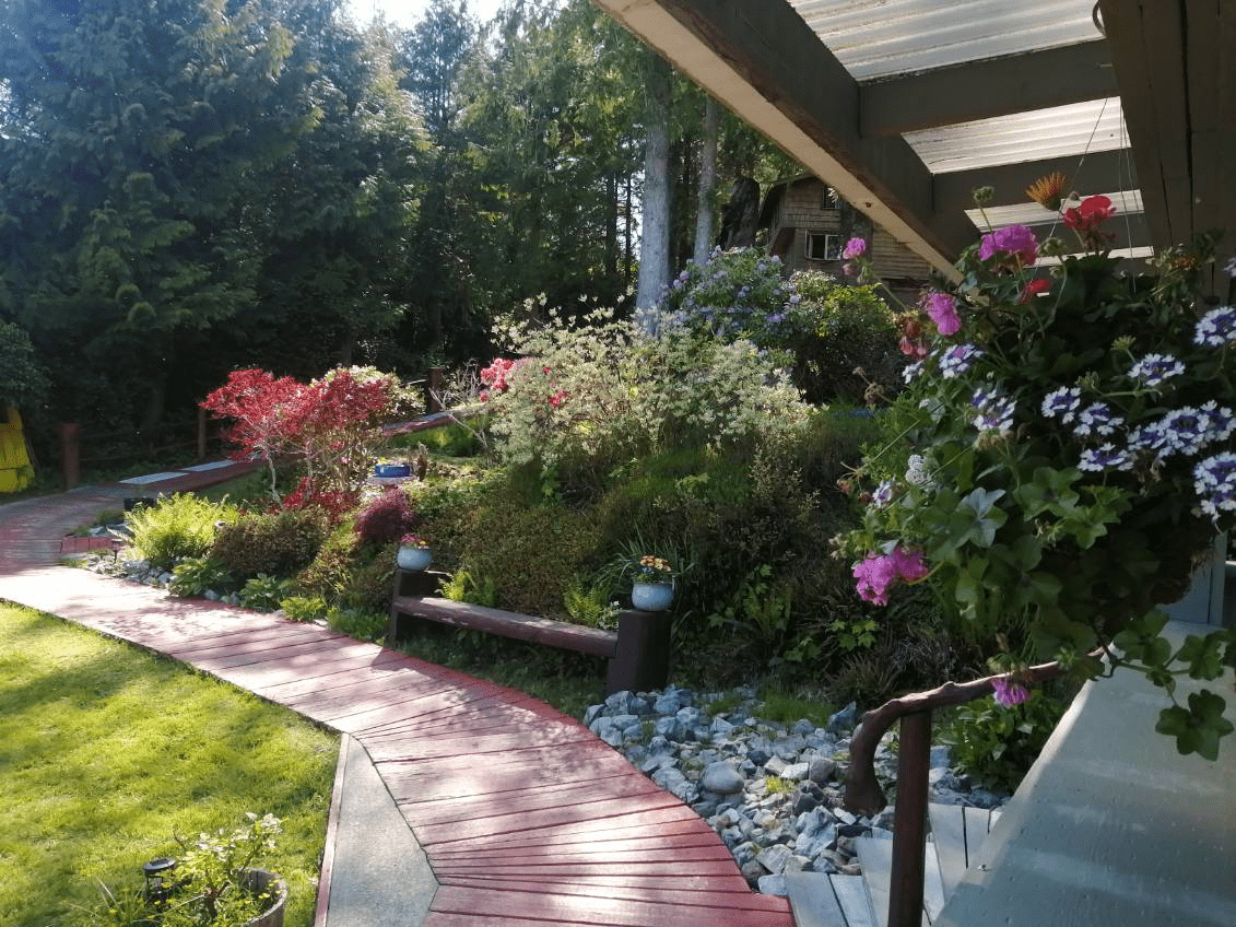 A brick walkway leading to a house with flowers on the side