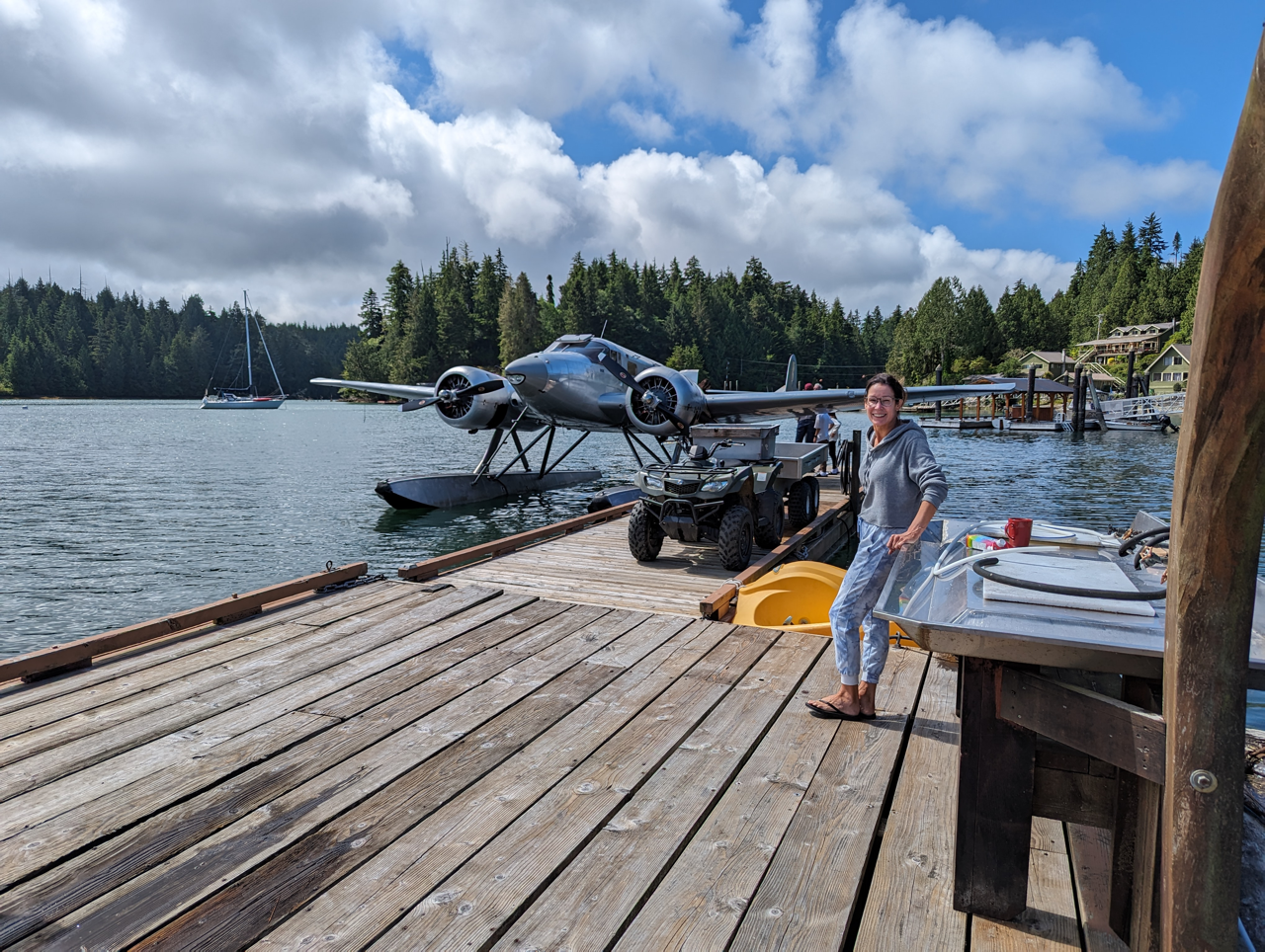 A woman is standing on a dock next to a seaplane.