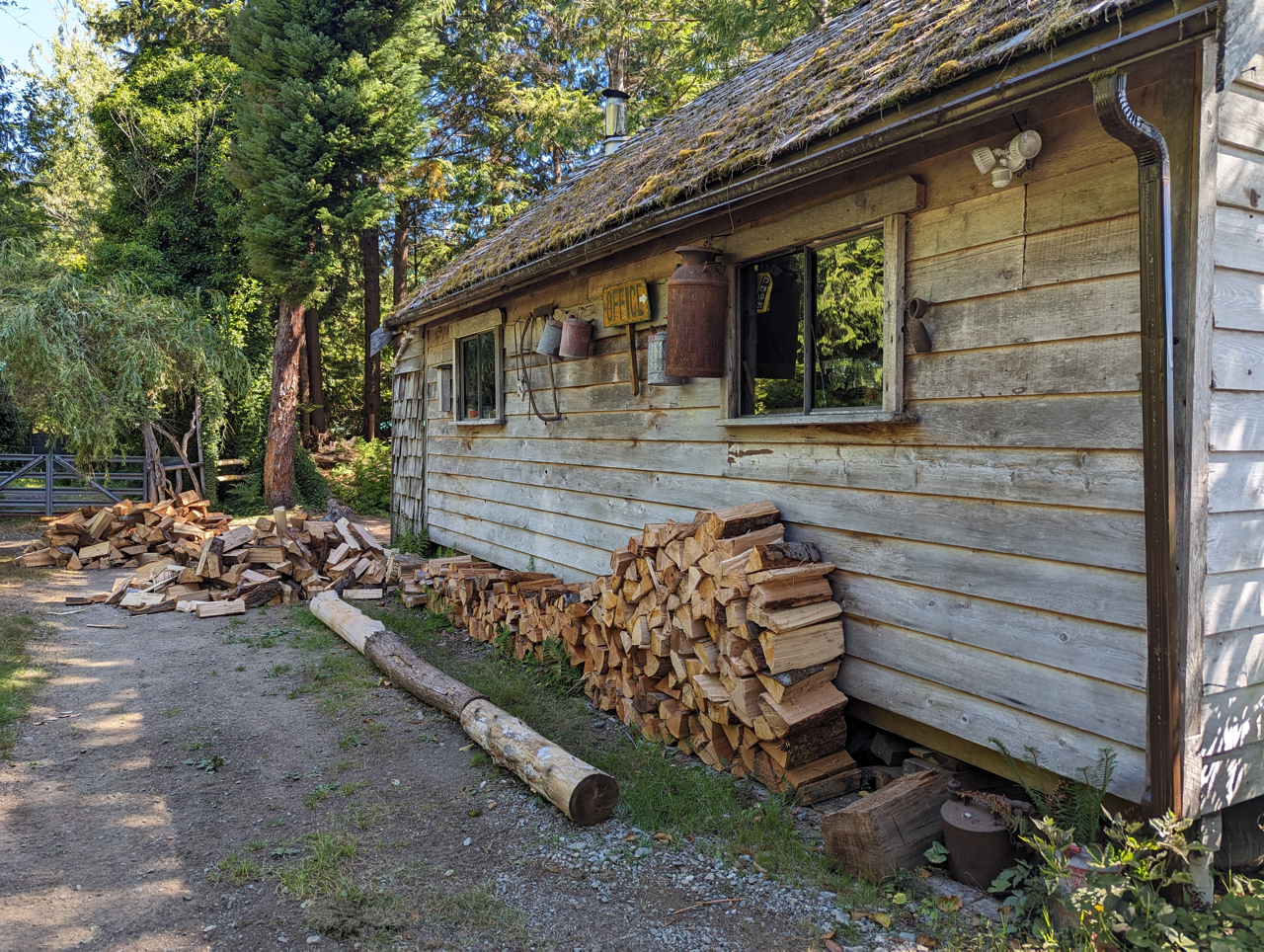 A pile of logs is sitting in front of a wooden building.