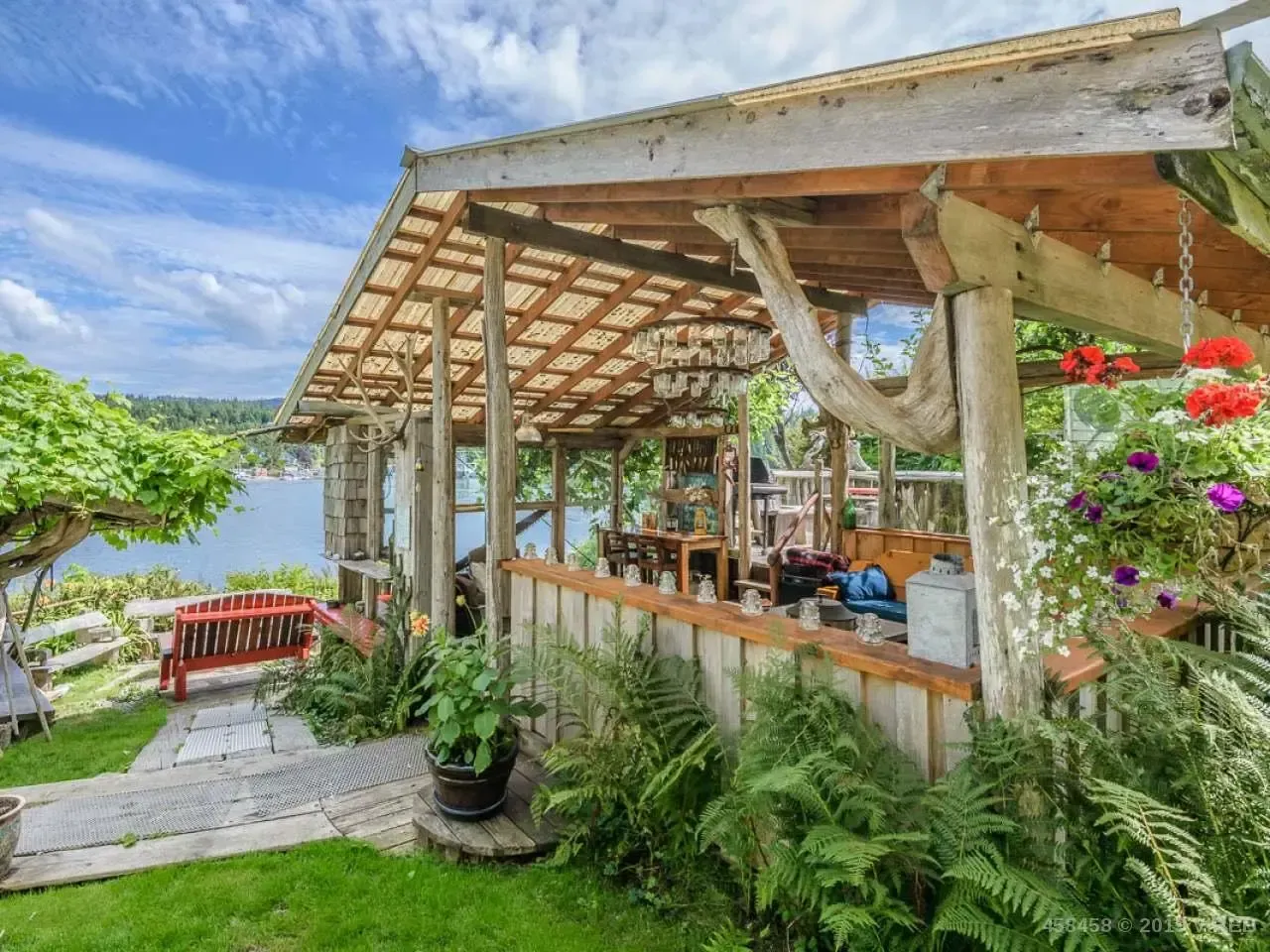 A wooden gazebo overlooking a body of water with a hammock hanging from the roof.