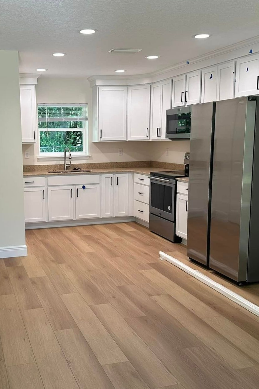 Couple with paint supplies in room with a ladder and window. Smiling as they prepare to paint.