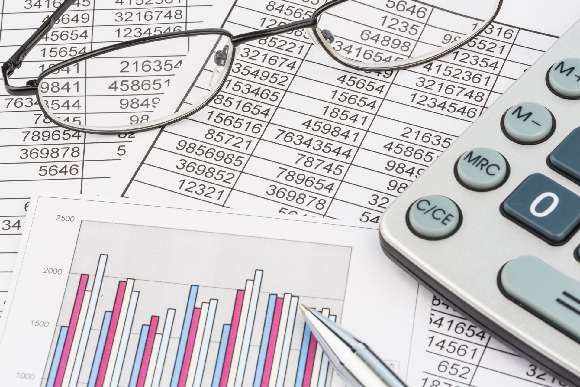 pile of spreadsheets with glasses on top