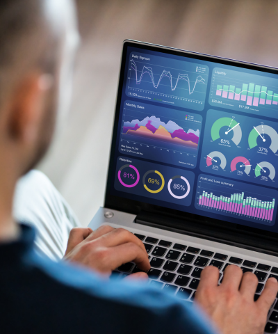 A person is typing on a laptop with a analytics dashboard on the screen