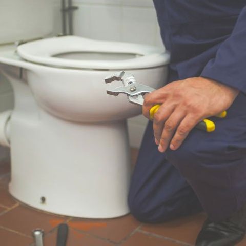 Plumber fixing a toilet bowl — Heaating Contractor in Downingtown, PA