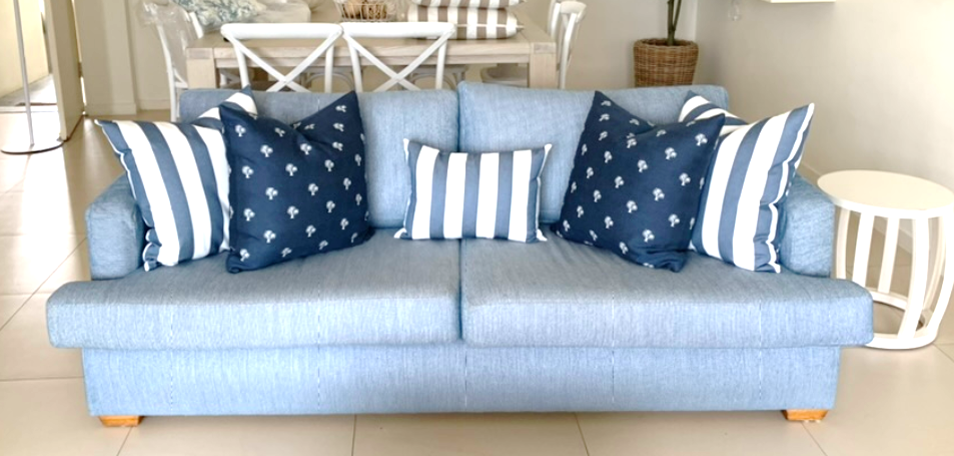 A blue couch with blue and white striped pillows in a living room.