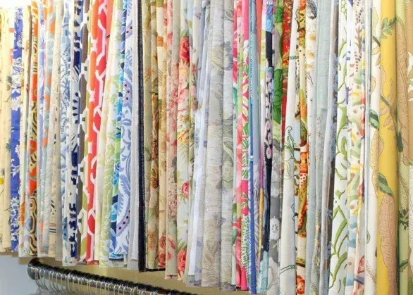 A bunch of fabrics are hanging on a rack in a store.