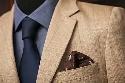 A man in a suit and tie with a pocket square in his pocket.