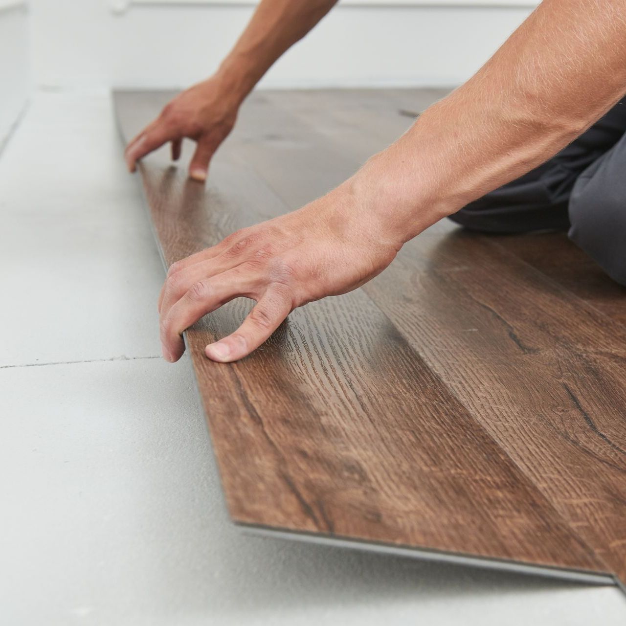 worker laying vinyl flooring material