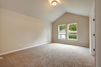 an empty bedroom with a vaulted ceiling and a carpeted floor .