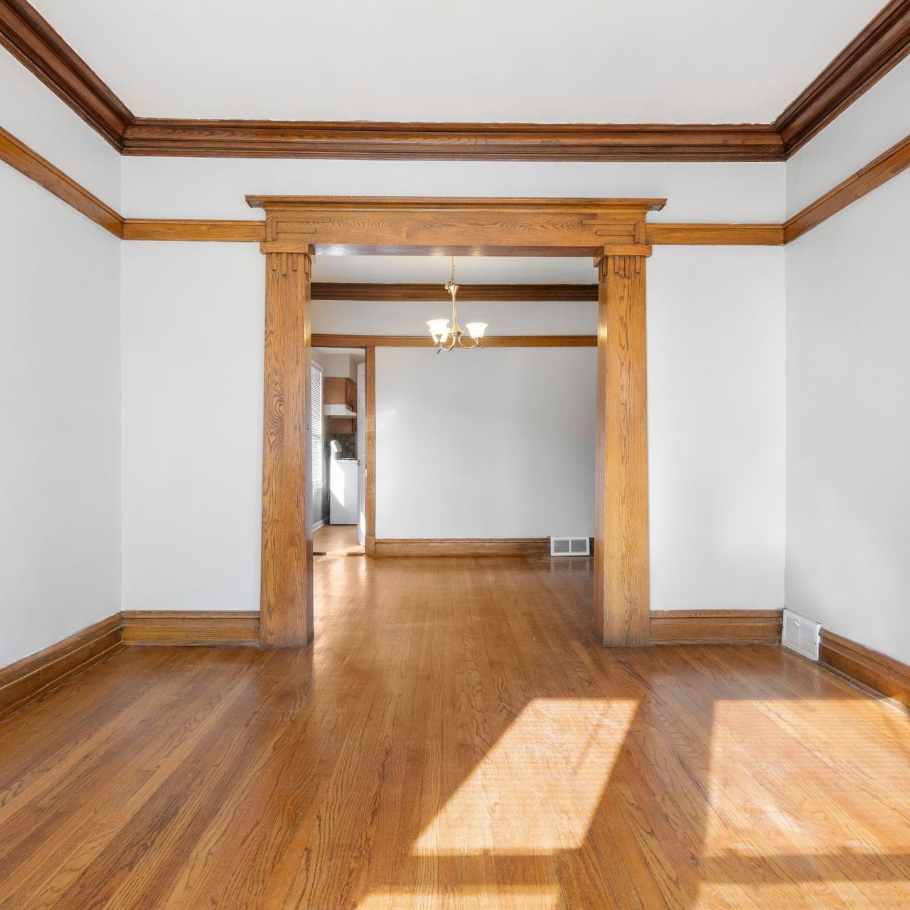 an empty living room with hardwood floors and white walls .