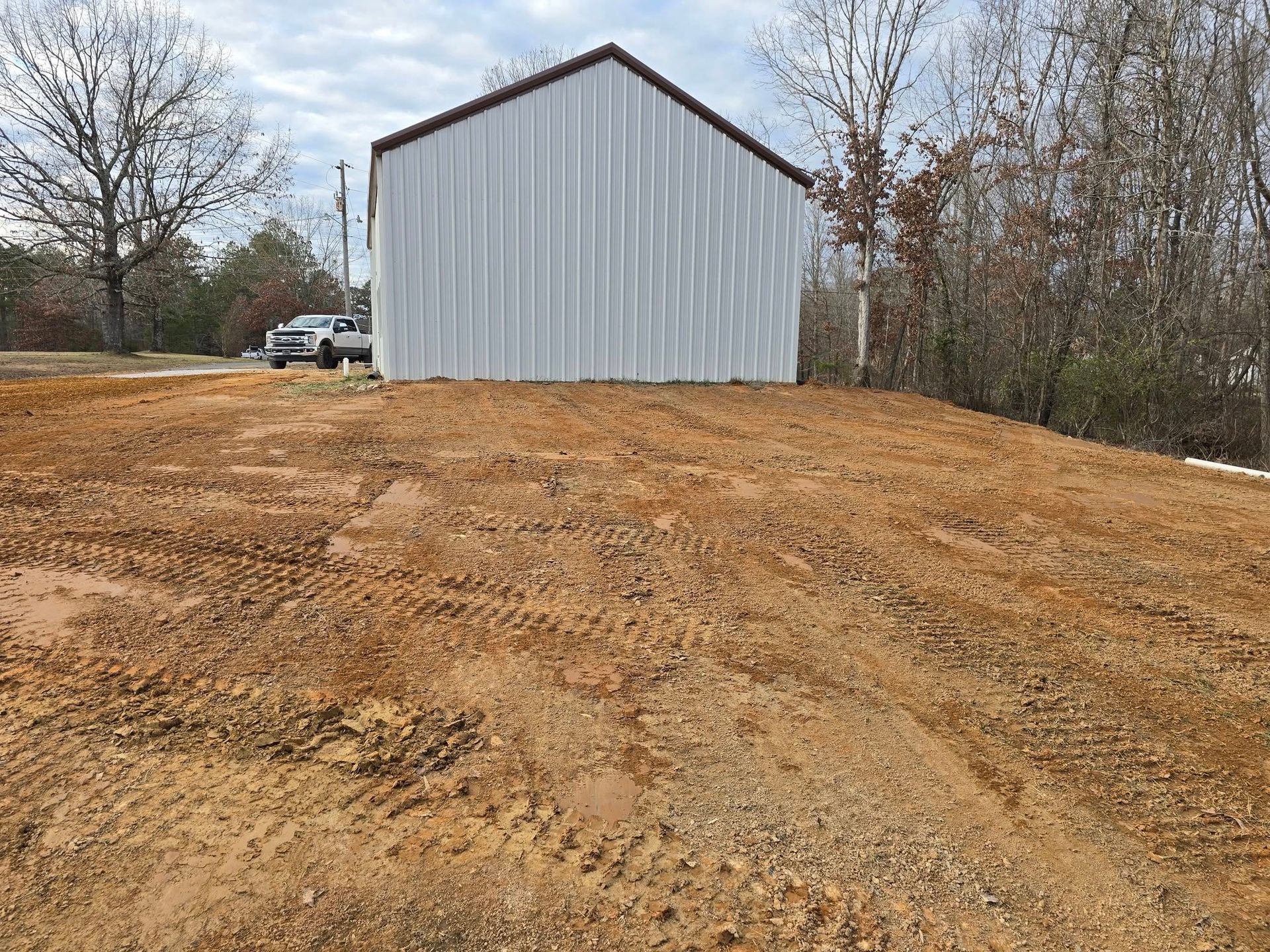 A large metal building with a brown roof sits on a mound of dirt.