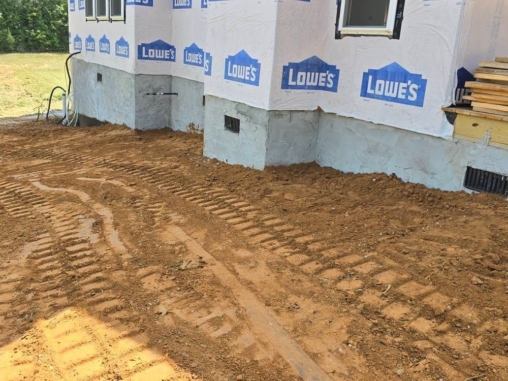 Construction site, a house foundation with mud and tire tracks. Blue Lowe's wrap on walls,