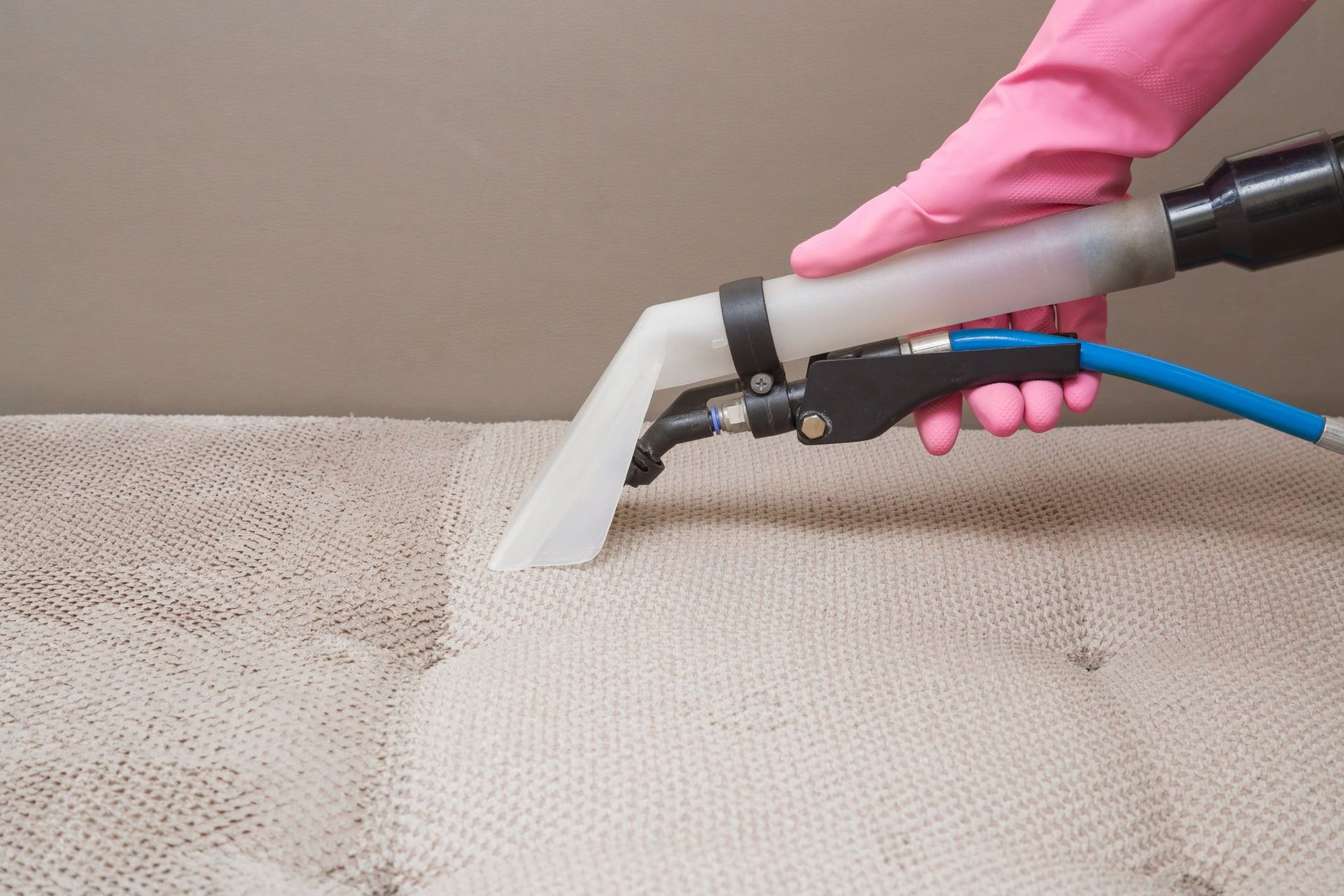 A person is cleaning a mattress with a vacuum cleaner.