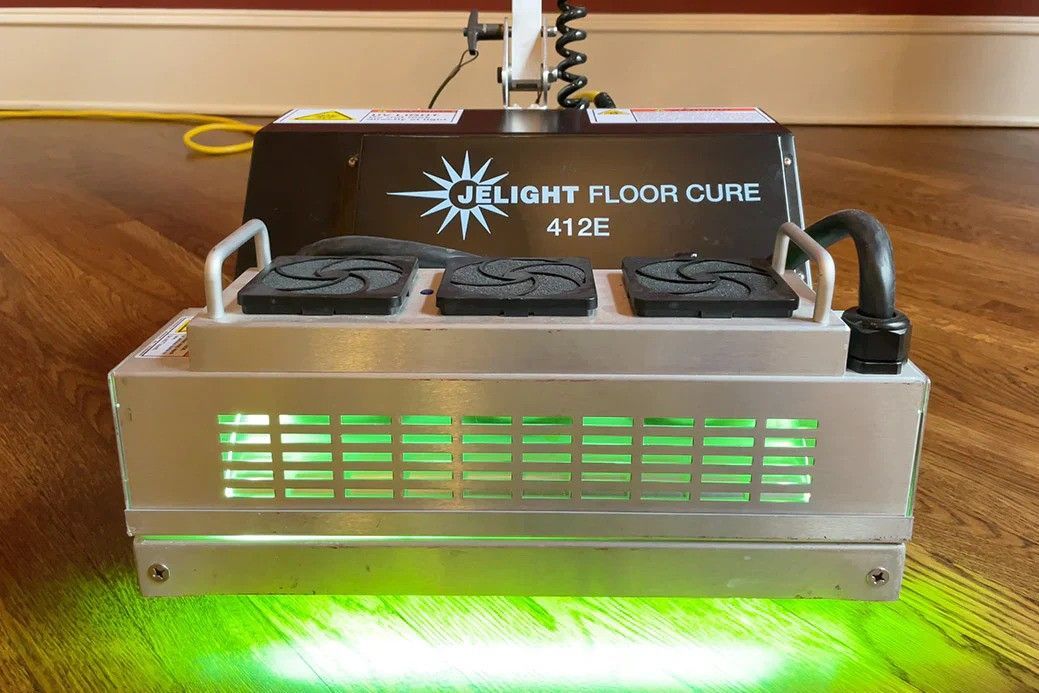 A machine is sitting on a wooden floor with green lights coming out of it.
