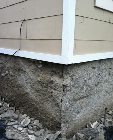 A foundation of a house under construction with red pipes in the sand.