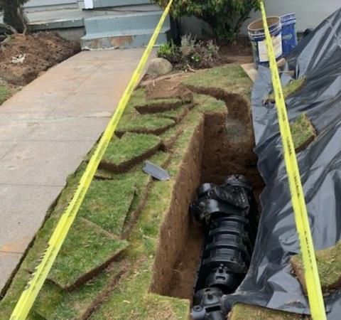 A foundation of a house under construction with red pipes in the sand.