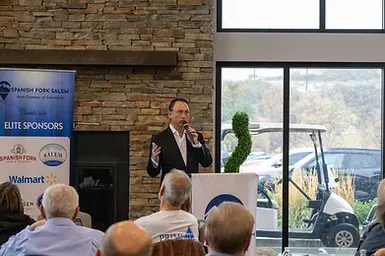 A man is standing at a podium giving a speech to a group of people.