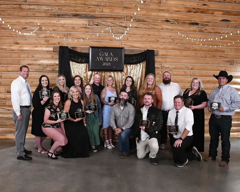 A group of people are posing for a picture in front of a wooden wall.