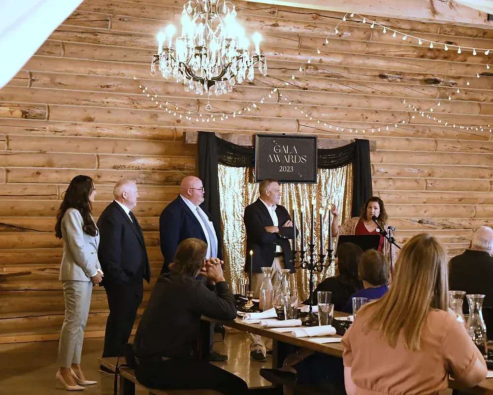 A group of people are sitting at a table in front of a wooden wall.