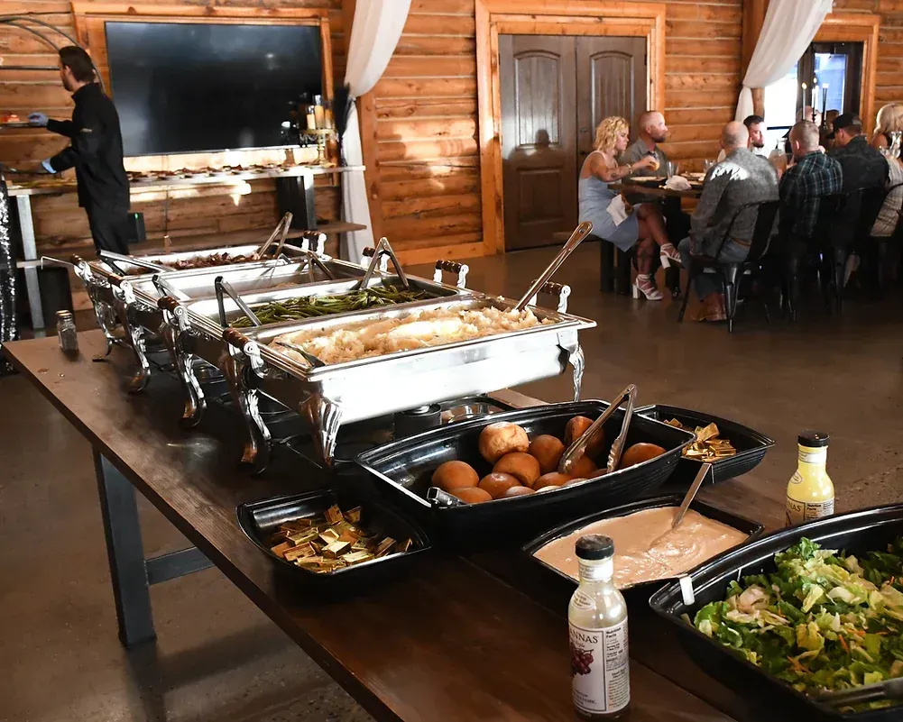 A buffet table filled with lots of food and people sitting at tables.