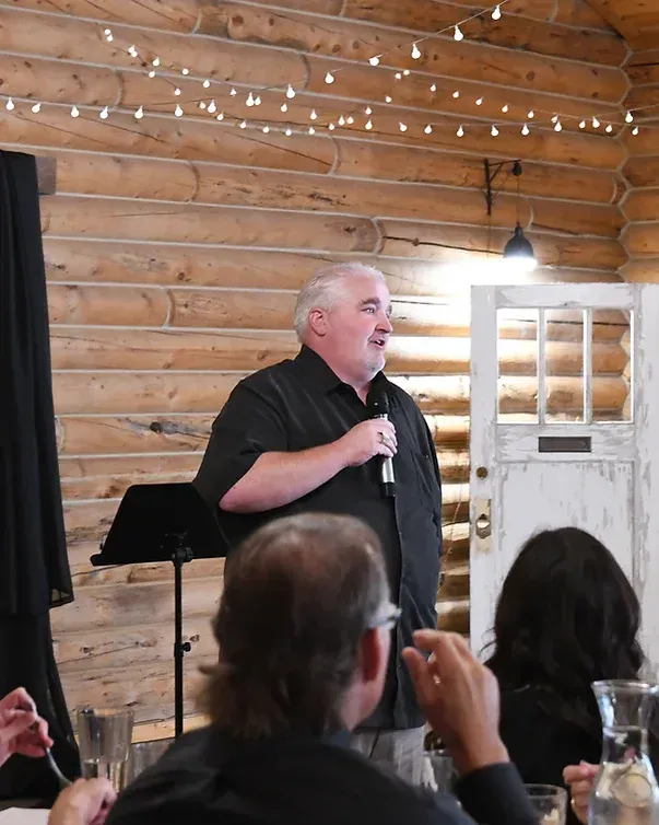 A man is speaking into a microphone in front of a group of people