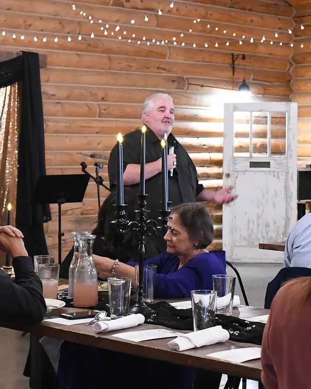 A man is giving a speech to a group of people at a table