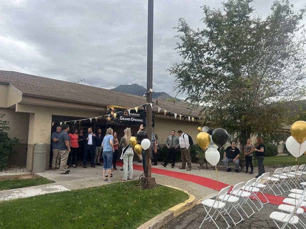 A group of people are standing in front of a building with balloons.