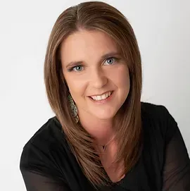A woman wearing a black shirt and earrings is smiling for the camera.
