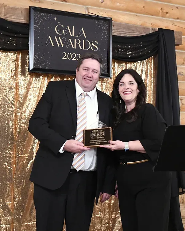 A man and woman are posing for a picture in front of a gala awards sign.