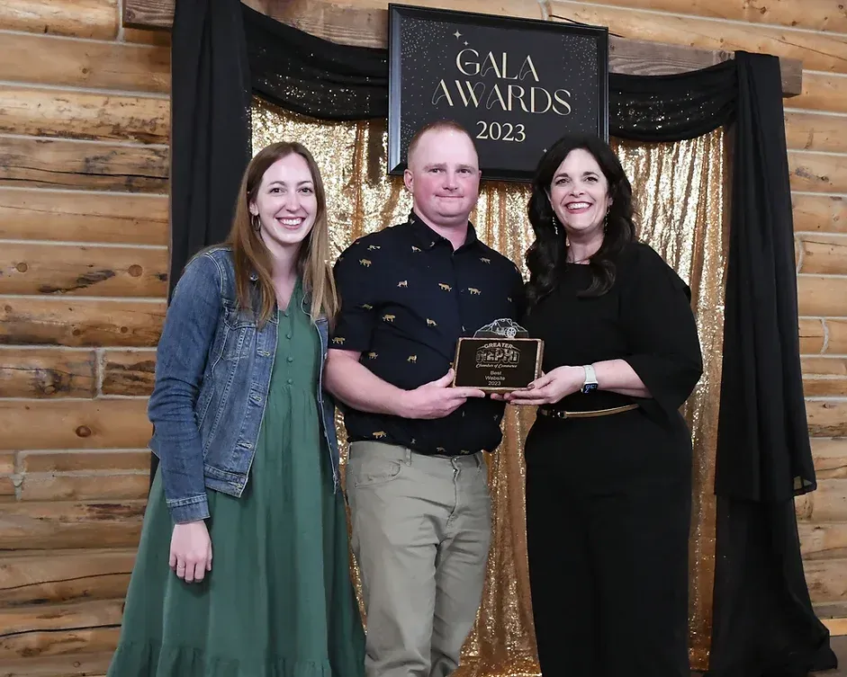 A man and two women are standing next to each other in front of a sign that says gala awards.