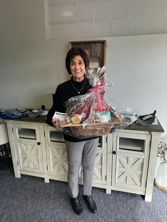 A woman is holding a gift basket in a living room.