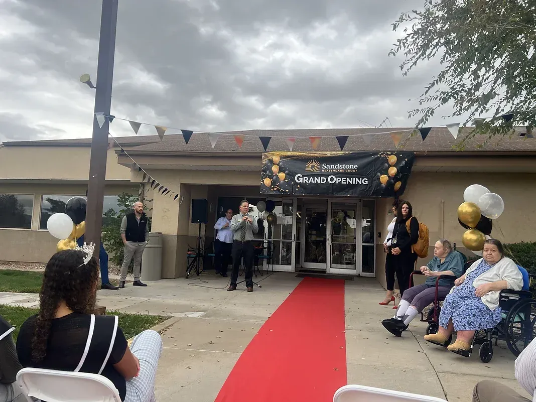 A group of people are sitting outside of a building on a red carpet.