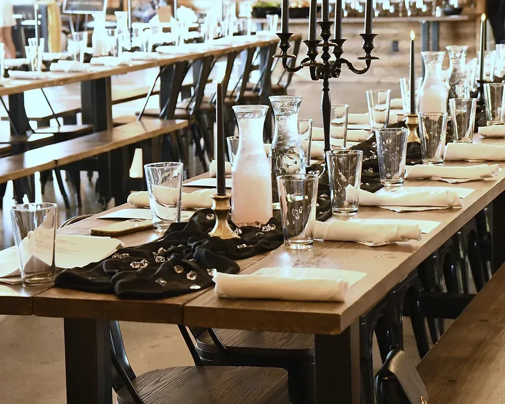 A long wooden table with glasses and candles on it