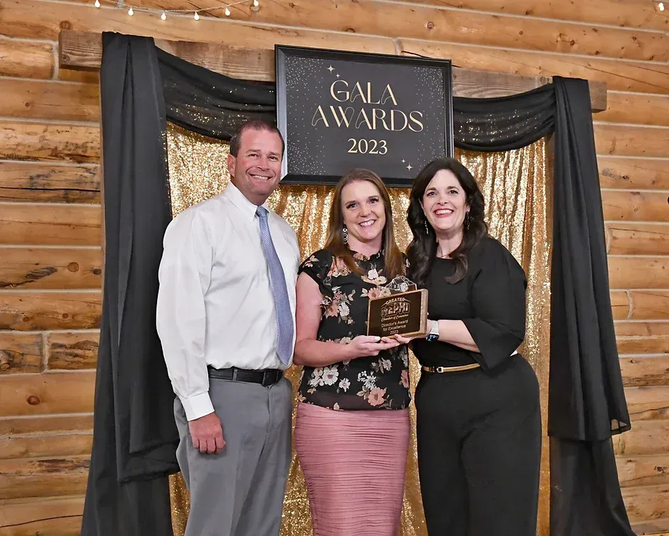 Three people are posing for a picture in front of a sign that says gala awards.