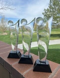 Three glass trophies are sitting on top of a brick wall.