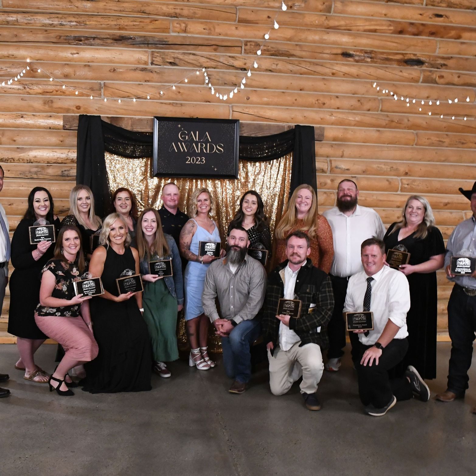 A group of people are posing for a picture in front of a wooden wall.