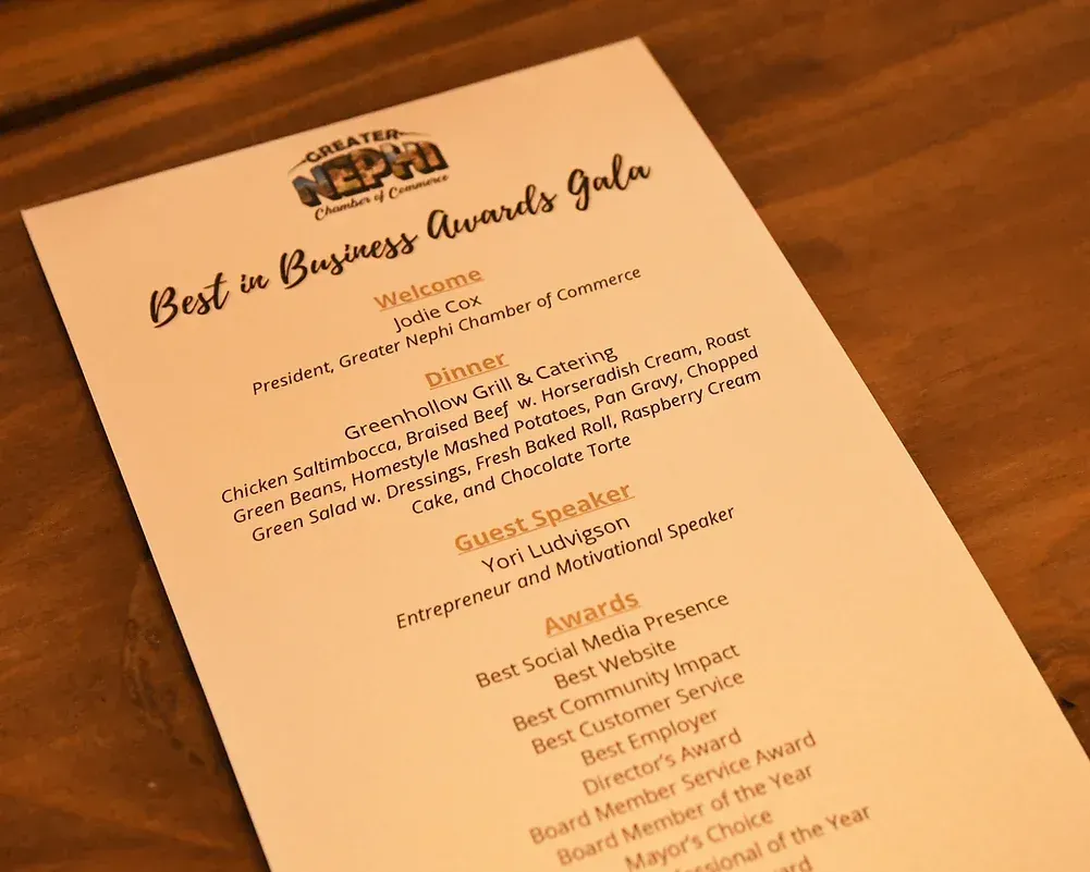 A menu for the best in business awards gala is sitting on a wooden table.