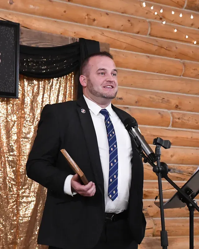 A man in a suit and tie is speaking into a microphone