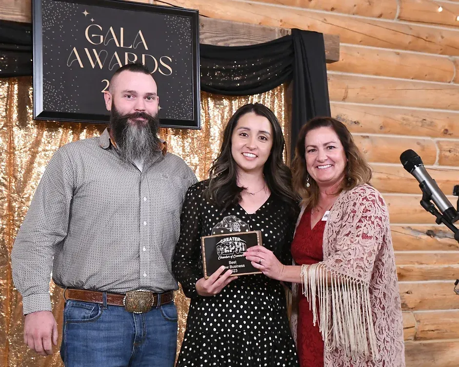 A man and two women are standing next to each other in front of a sign that says gala awards.