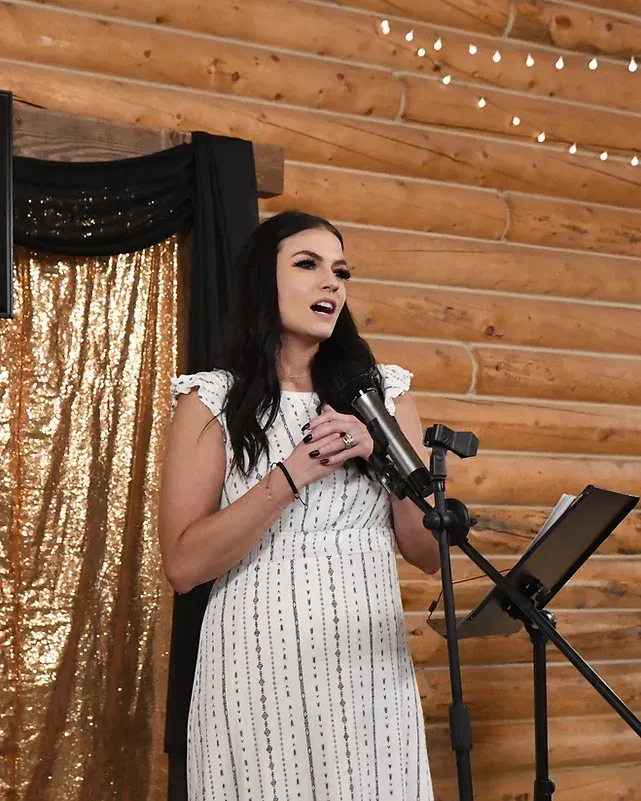 A woman in a white dress is singing into a microphone