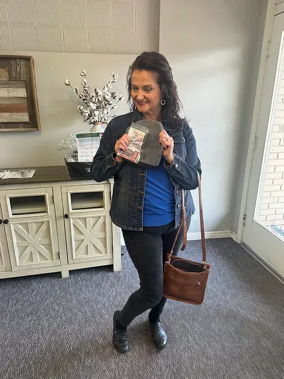 A woman is standing in a room holding a bag of money.