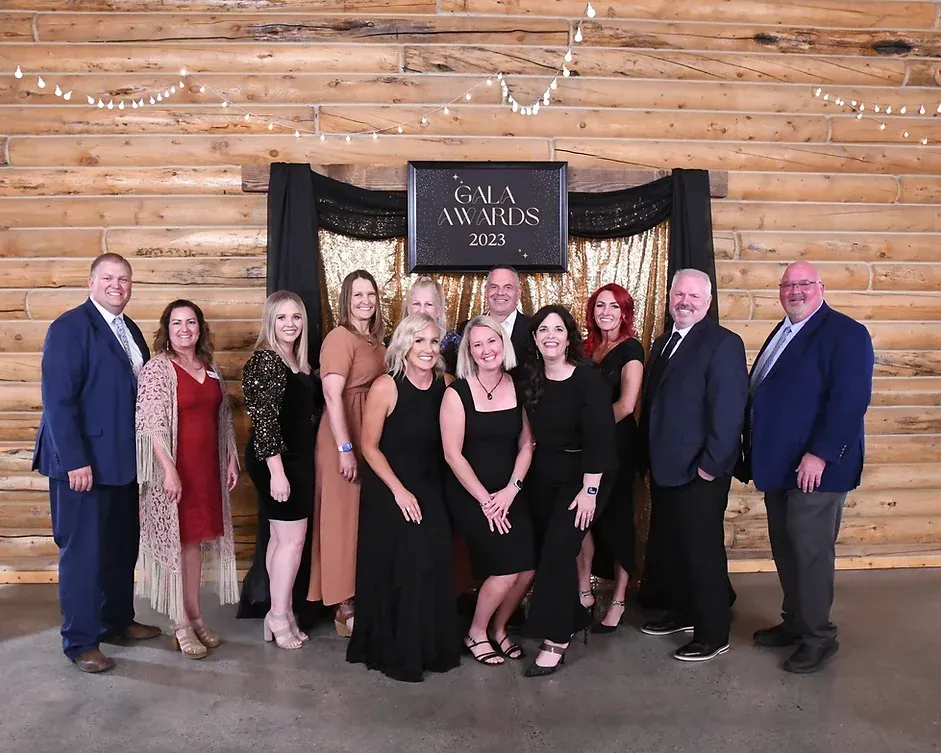 A group of people are posing for a picture in front of a wooden wall.