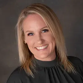 A woman is smiling for the camera and wearing a black shirt.