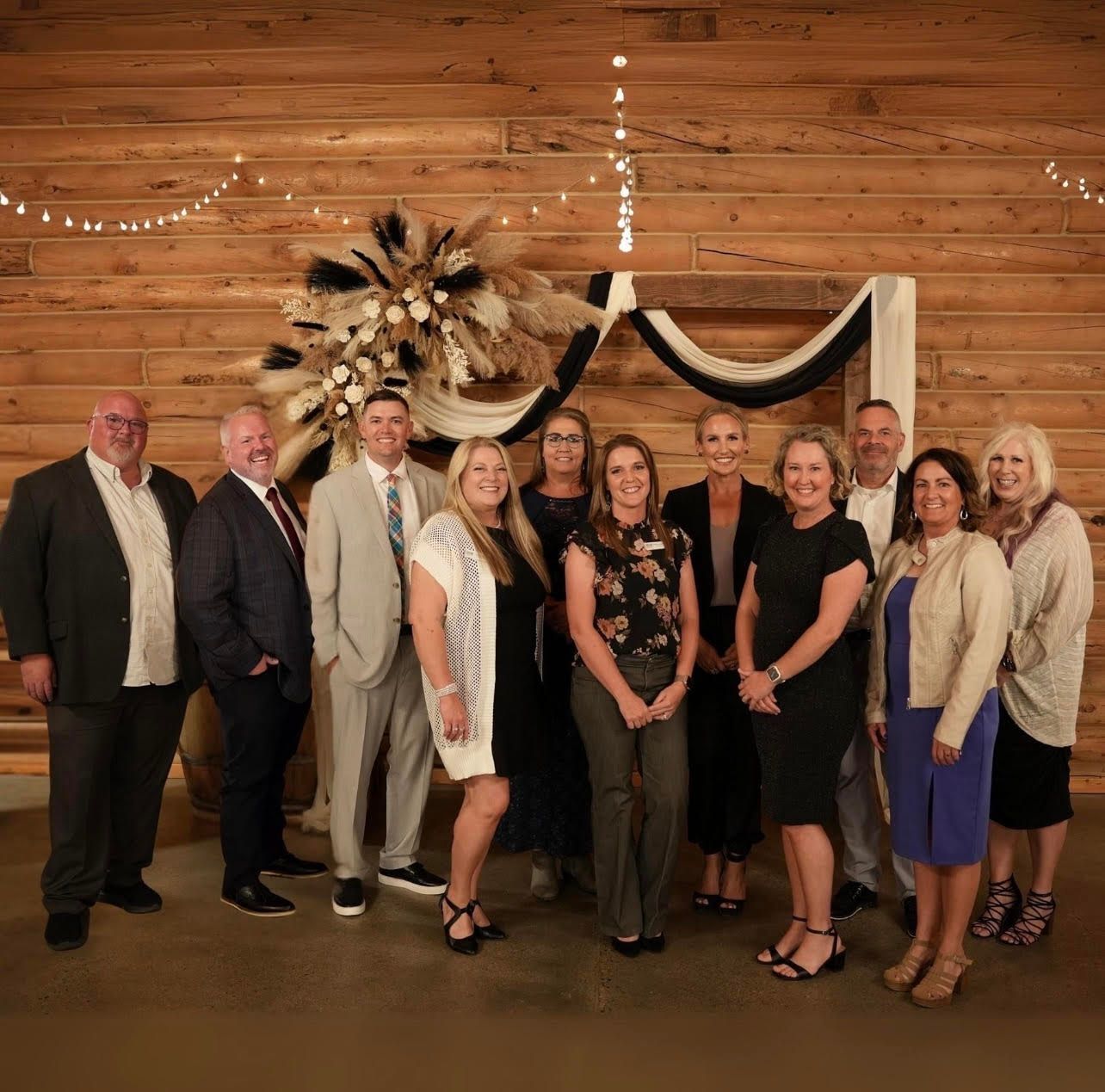 A group of people are posing for a picture in front of a wooden wall.
