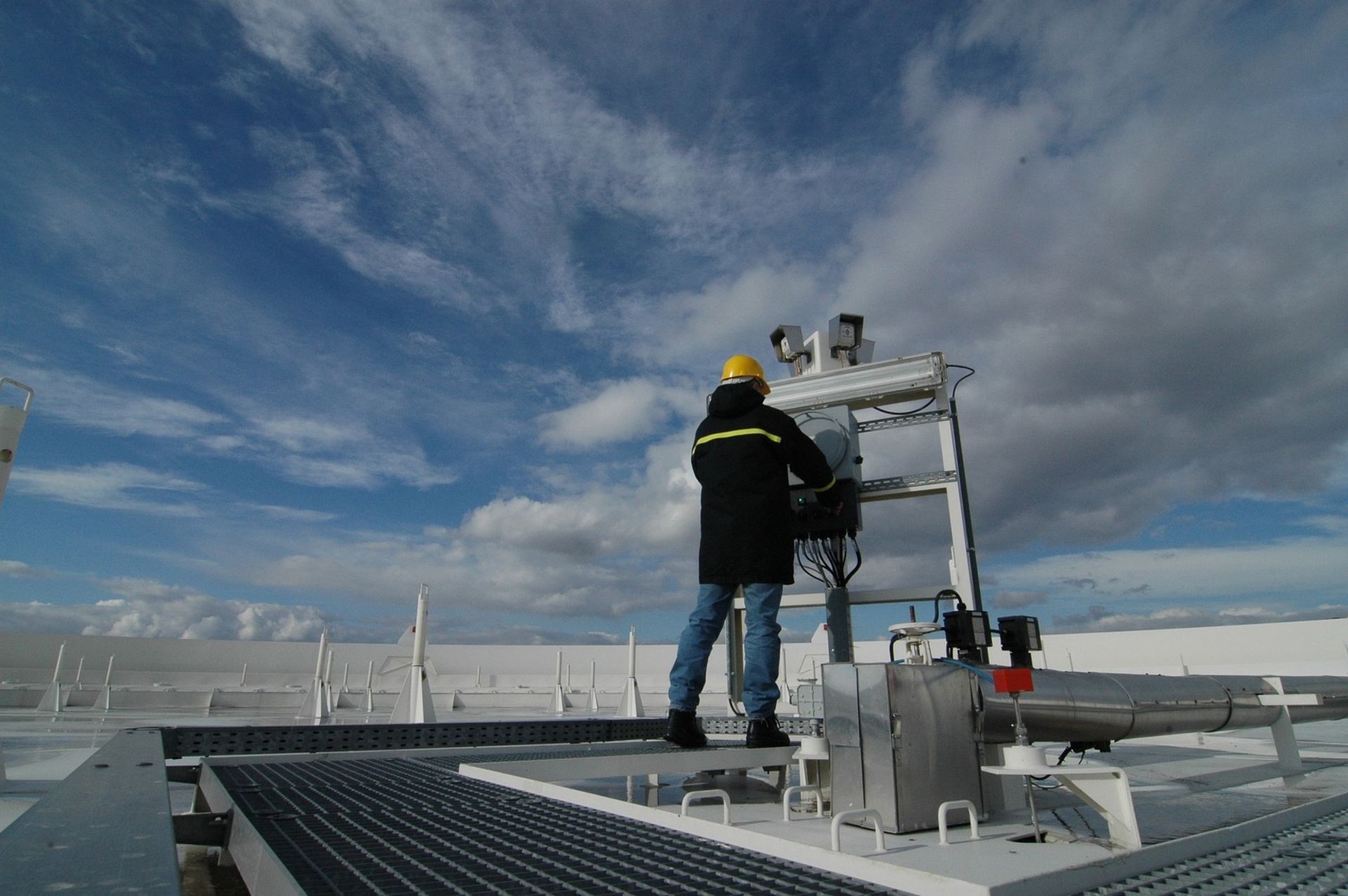 A man in a hard hat is standing on a metal platform