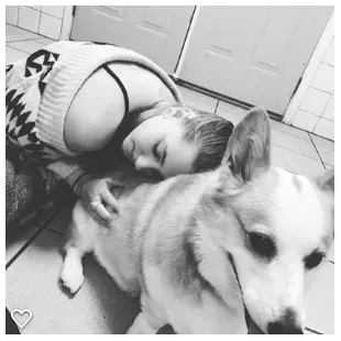 A woman is laying on the floor with her head on a dog