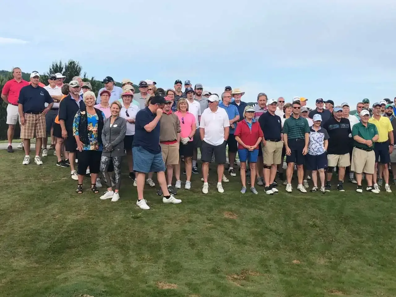 A large group of people are posing for a picture on a golf course.
