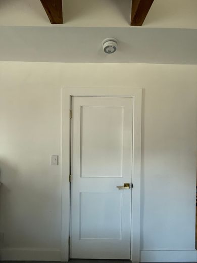 A white door in a room with wooden beams on the ceiling.