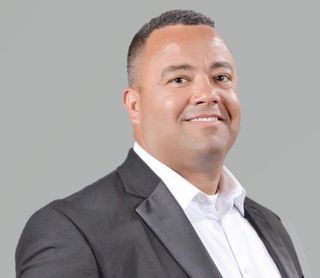 A man in a suit and white shirt is smiling for the camera.