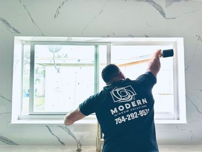 A man is cleaning a window with a hammer.